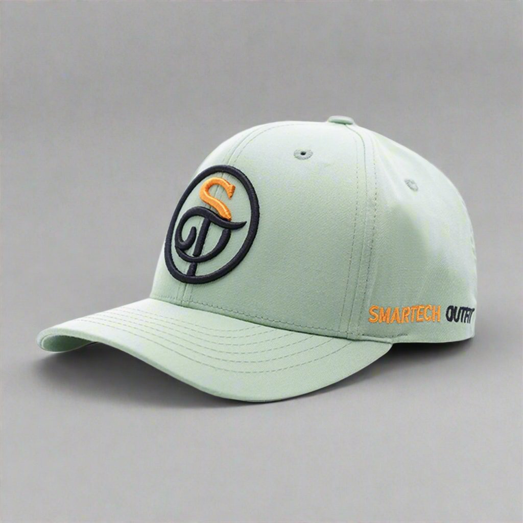 An olive green cotton baseball cap featuring an embroidered black and orange logo on the front and the text "Smartech Outfit" on the side. Known for its brand quality, this cap has a curved brim and vent holes on the top panels.